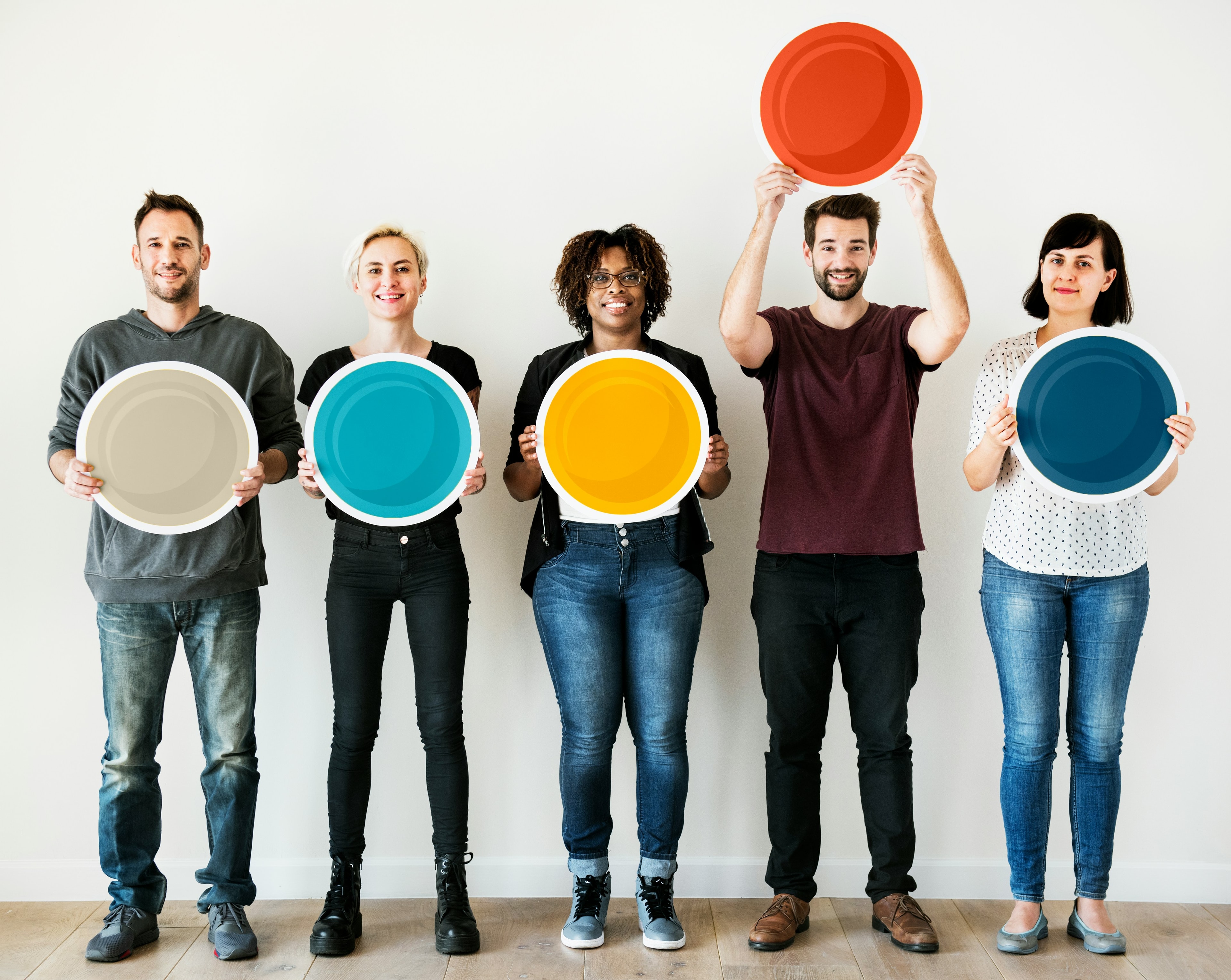 Five diverse people standing together holding colourful circular plates