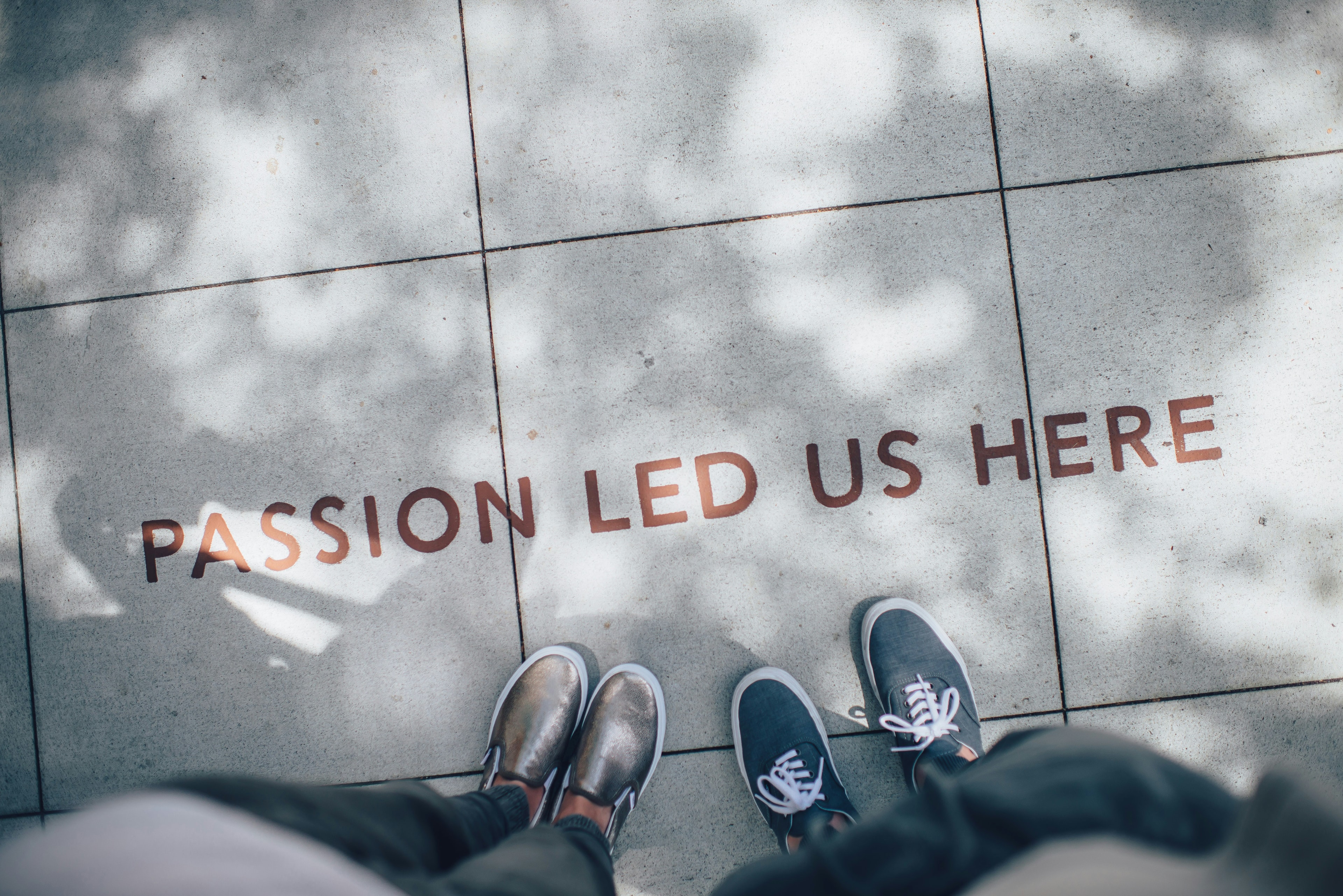 Two people standing on pavement with the words 'Passion Led Us Here'